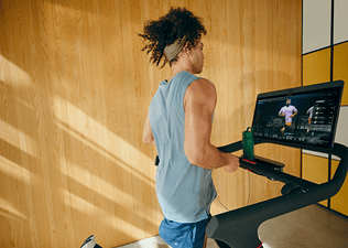 Man running on a Peloton treadmill doing a guided running workout.