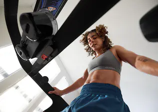 Woman working out on a Peloton Cross Training Tread wondering why running is so hard.