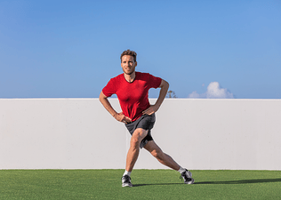 Man practices a curtsy lunge exercise outdoors 