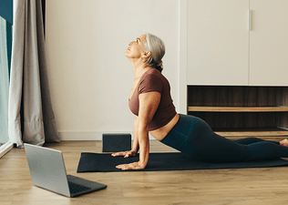 Woman practices Upward-Facing Dog pose on her yoga mat at home