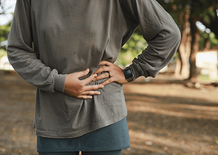 A close-up photo of a runner pressing down on their left side to help get rid of a side stitch.