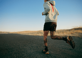 Man wondering how many miles a week he should run while running outside on a gravel road. 