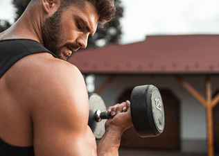 A man performing a bicep curl with a dumbbell outside while training to failure.