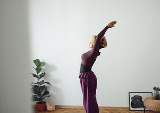Woman does morning stretches in bright morning light at home