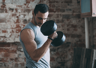 A man doing a single-arm bicep curl with a dumbbell. He is looking at his arm to enhance the mind-muscle connection.