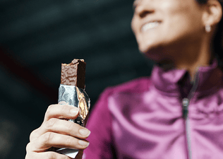 An close-up photo of an athlete holding a candy bar that she's taken a bite out of before her workout.