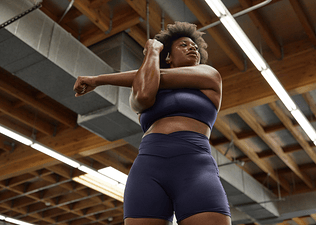 Woman stretches at the gym; stretching can be part of a deload week