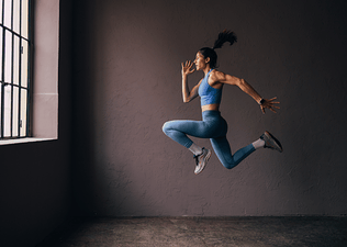 Woman does a jumping exercise indoors, an explosive exercise 