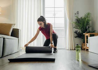 Woman unrolls a yoga mat to practice yoga for cyclists