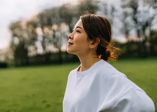 A woman with inner strength. She is standing outside and looking ahead confidently. 