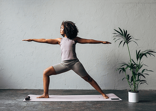 Woman practices Warrior 2 Pose during a yoga for athletes practice