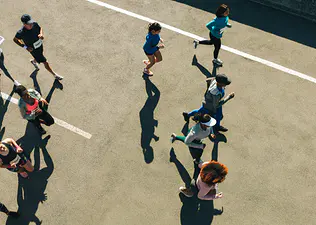 Group of people during a road race, including some people running and some people walking the marathon.