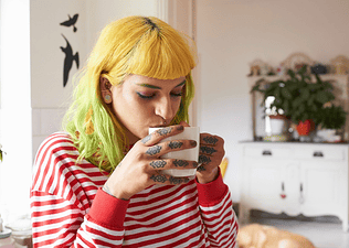 A young woman drinking coffee from a mug.