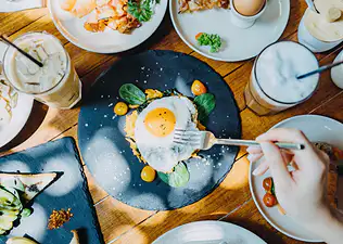 Birds-eye view of someone eating a sunny-side-up egg (a complete protein) at an outdoor restaurant.