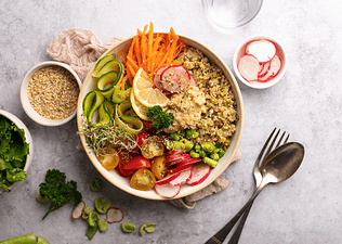 A colorful buddha bowl with non-meat protein sources like quinoa, edamame, and hummus, among other veggies.