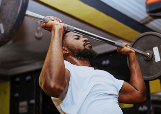 A man lifting a barbell at the gym.