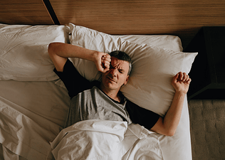 A man waking up and stretching his arms after having vivid dreams after exercise.