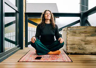A woman in an upright seated position meditating outside. She is sitting upright to prevent herself from falling asleep during meditation. 