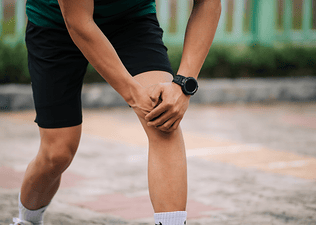 Is running bad for your knees? Man holds his knee while pausing during a run