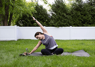 Woman does a side stretch while seated outdoors