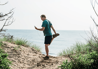 Man looks at phone while exercising outdoors