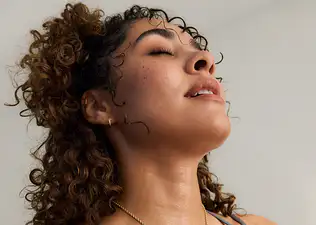 A woman practicing breathwork. She's breathing deeply through her mouth and closing her eyes.
