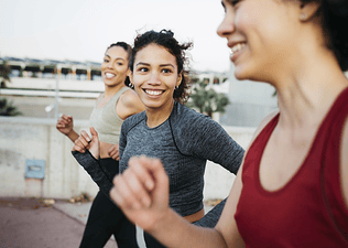 A group of three women practicing social wellness by going on a power walk outside together.