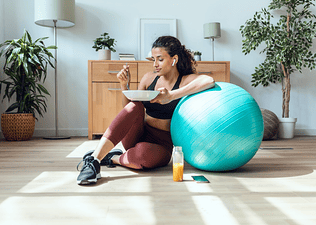 A woman eating a meal that has amino acids for muscle growth in it after a workout.