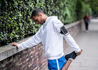 Man does an it band stretch before heading out on a run