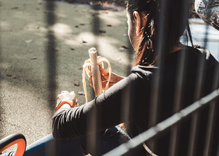 A back view of a runner sitting outside on a step and eating a banana. Bananas are great high-carb foods for runners.