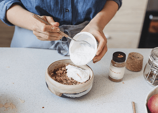 A woman adding Greek yogurt to her overnight oats in order to get more protein.