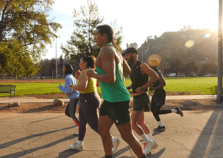A local fitness club going for an outdoor run together at a park.
