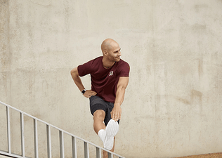 Man in workout gear stretching his hamstring on a handrail
