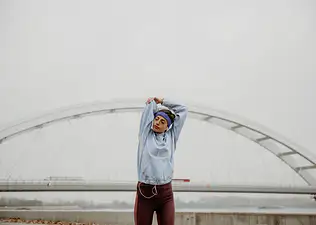 Woman does shoulder mobility exercises outside