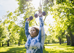 Woman does dumbbell shoulder exercises outside 