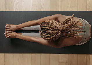 Woman weighs Pilates vs. barre while warming up for her workout on a mat