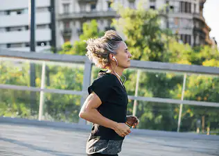 A mid-age woman running outside on a sunny day.