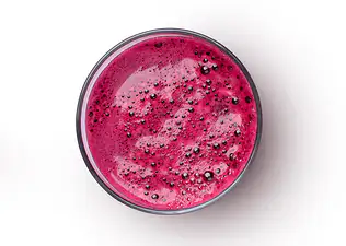 A bird's-eye view of a glass of beet juice on a white background.