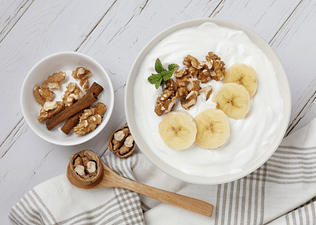 A bowl of Greek yogurt with banana and walnuts.