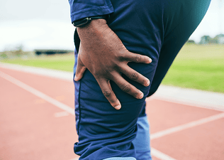 A close-up photo of a man holding his thigh as he experiences a muscle twitch after a workout.