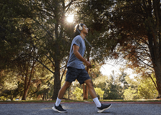  A person with headphones on walking on a path surrounded by trees