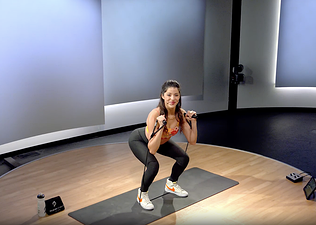 Peloton instructor Hannah Corbin doing a resistance band squat exercise.