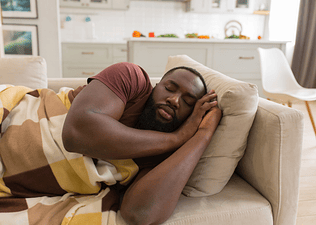 A man taking a power nap on a couch.