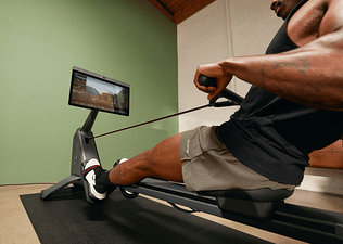 man learning how to use a rowing machine on a Peloton Row scenic class