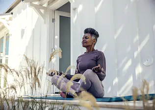 A woman outside practicing meditation before exercise.