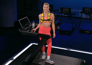 Peloton instructor Rebecca Kennedy poses on the Peloton Tread+ before teaching a weighted vest walking class.