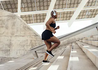 A woman running up a set of outdoor stairs in warm weather.