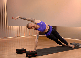 Peloton instructor Kirra Michel demonstrates a side plank during a yoga class on the Peloton App