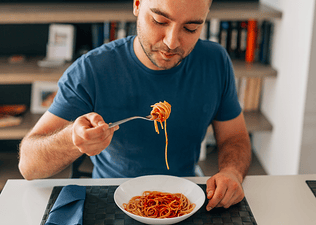 A man eating spaghetti as he carb loads.