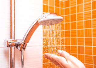 A hand checking the temperature of a shower after a workout.